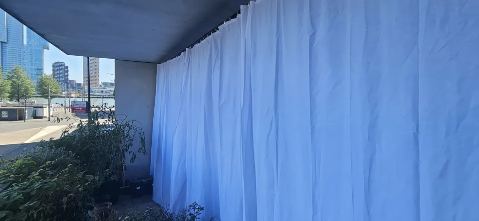 Balkon in Rotterdam met witte doeken als zonwering aan een staalkabel
